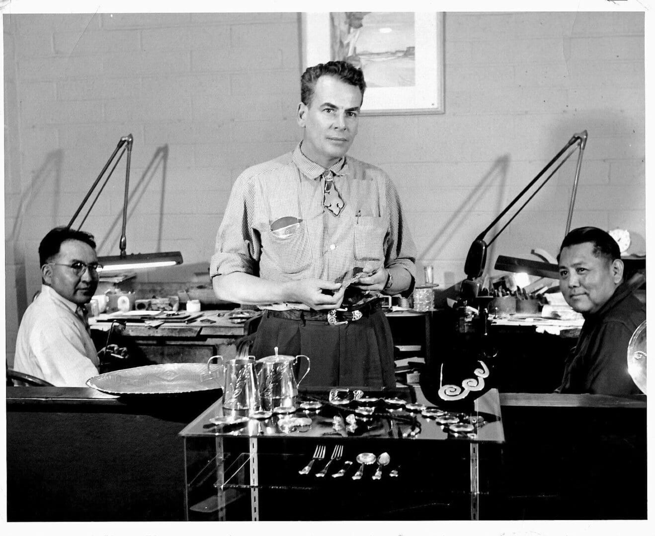 Three men in a silver jewelry workshop.