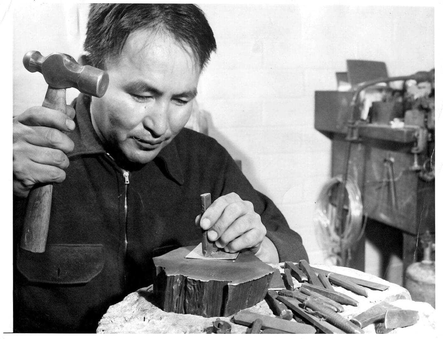 Man carving wood with hammer and chisel.
