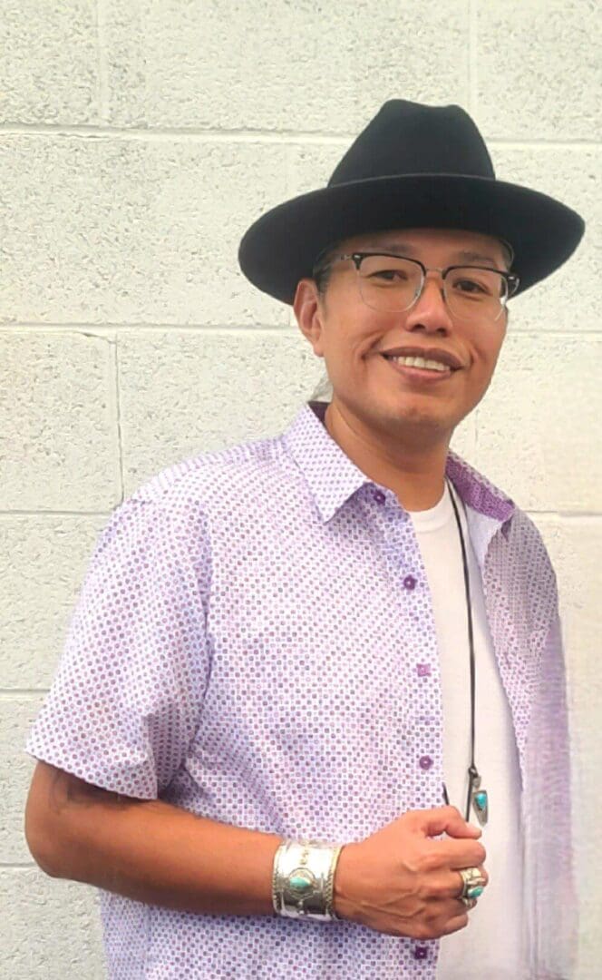 Man wearing hat and glasses, smiling warmly.