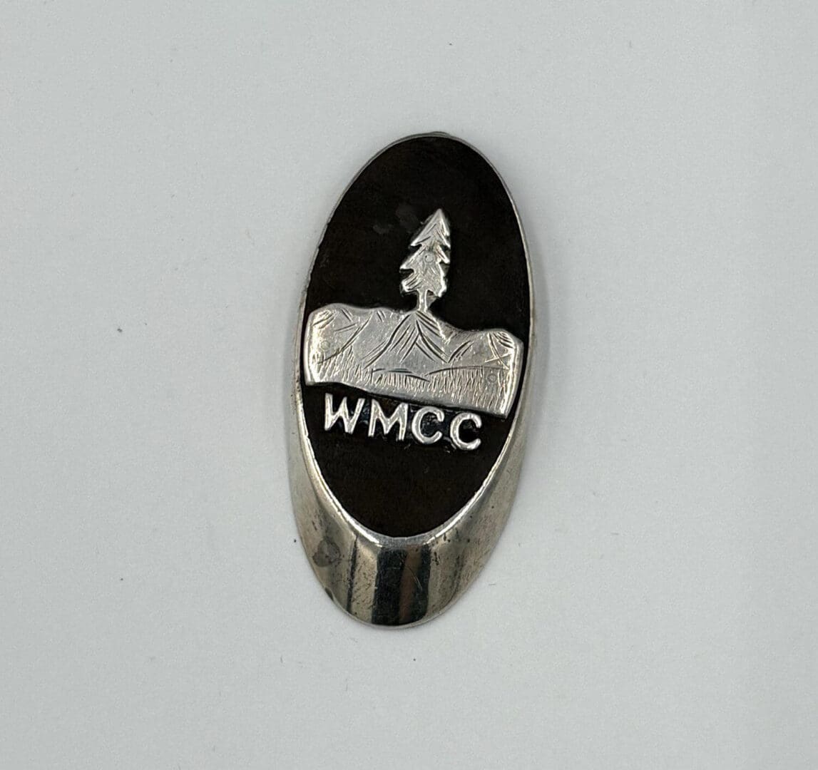 Silver oval badge with WMCC engraving.