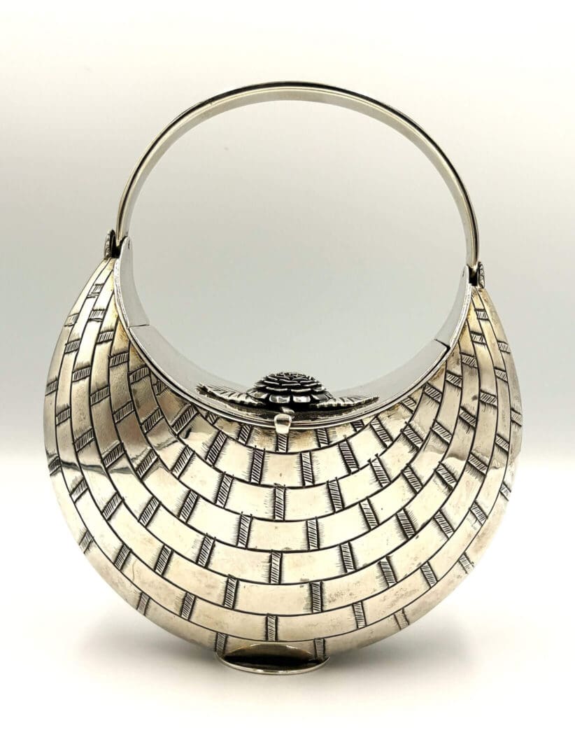 Woven-pattern silver handbag with circular handle.