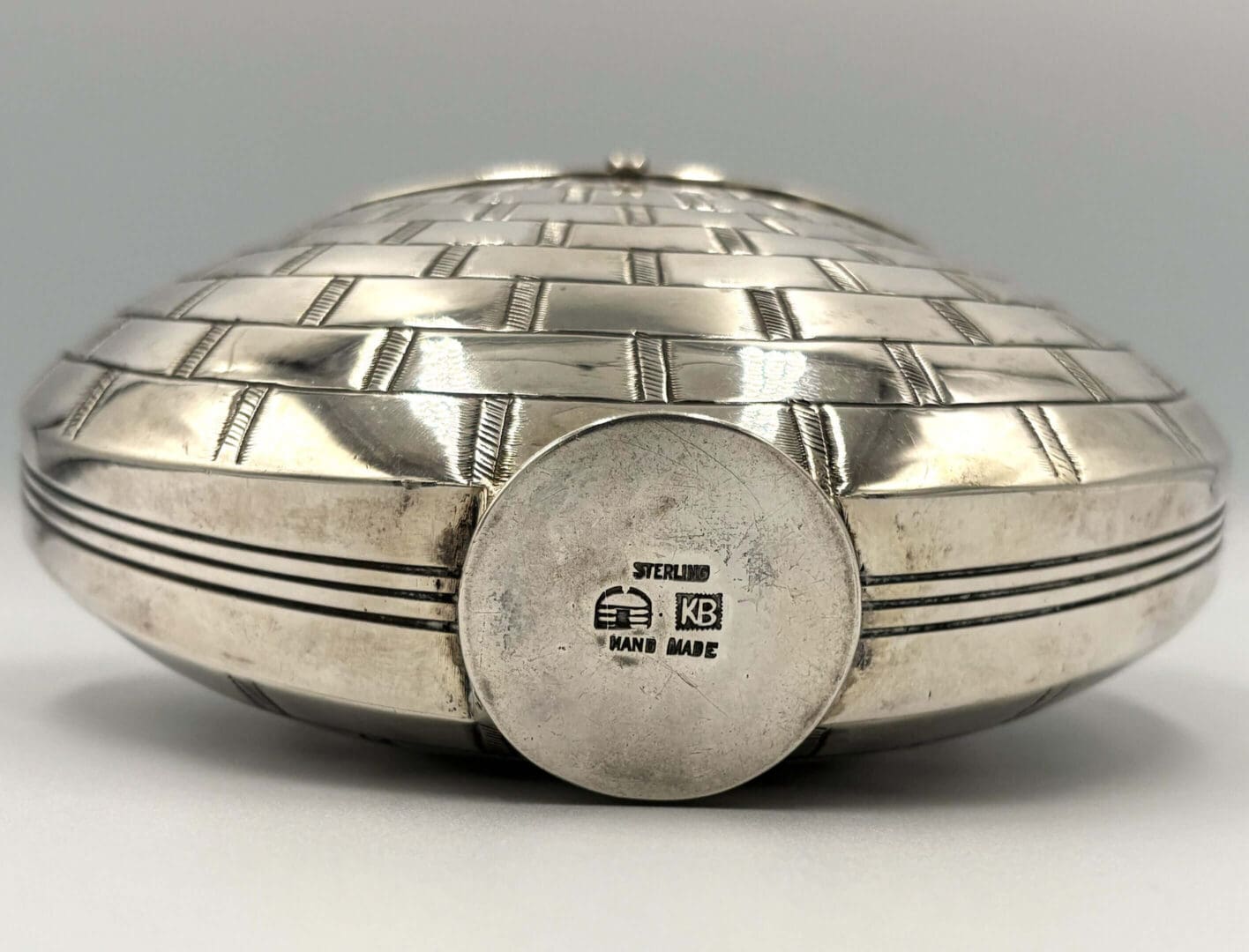 Silver handmade decorative container with engraved markings.