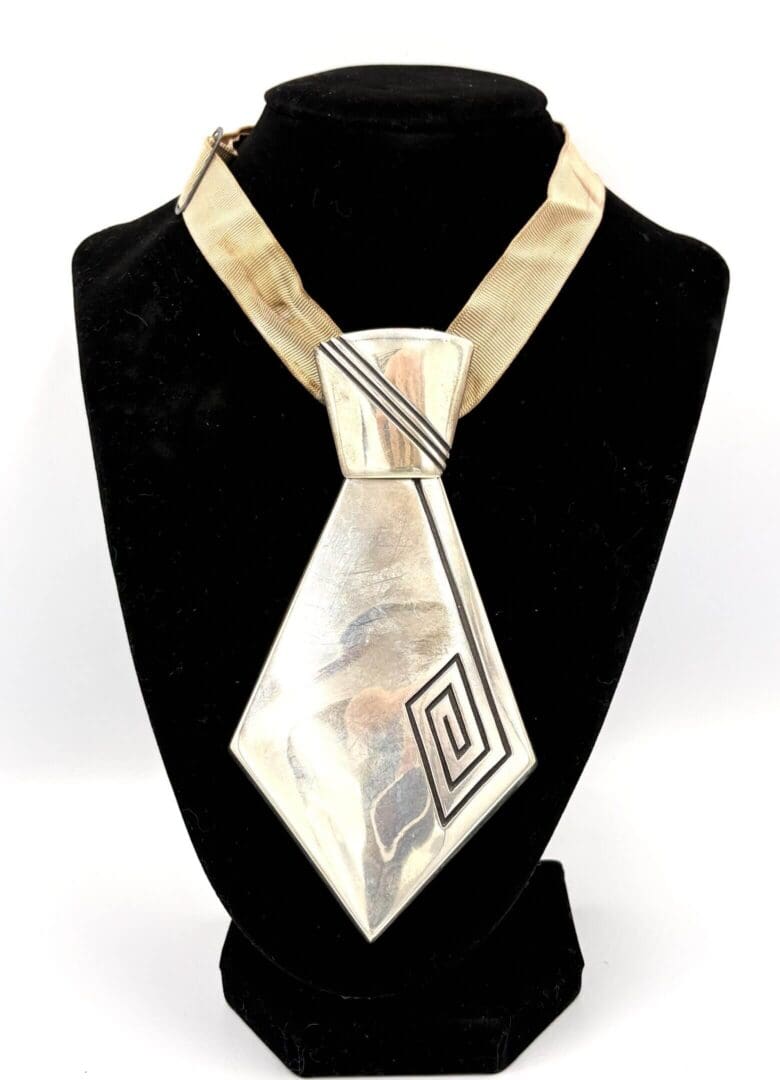 Silver geometric pendant on gold necklace display.