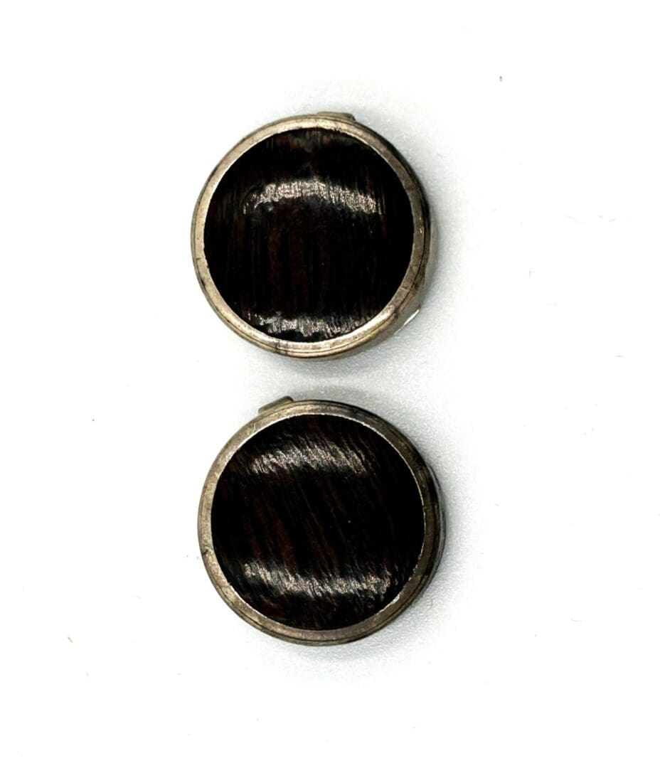 Two round, dark, reflective cufflinks on white.