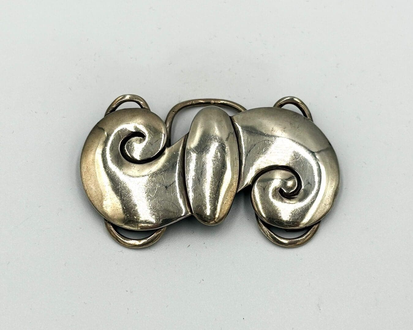 Silver abstract swirl design metal brooch.