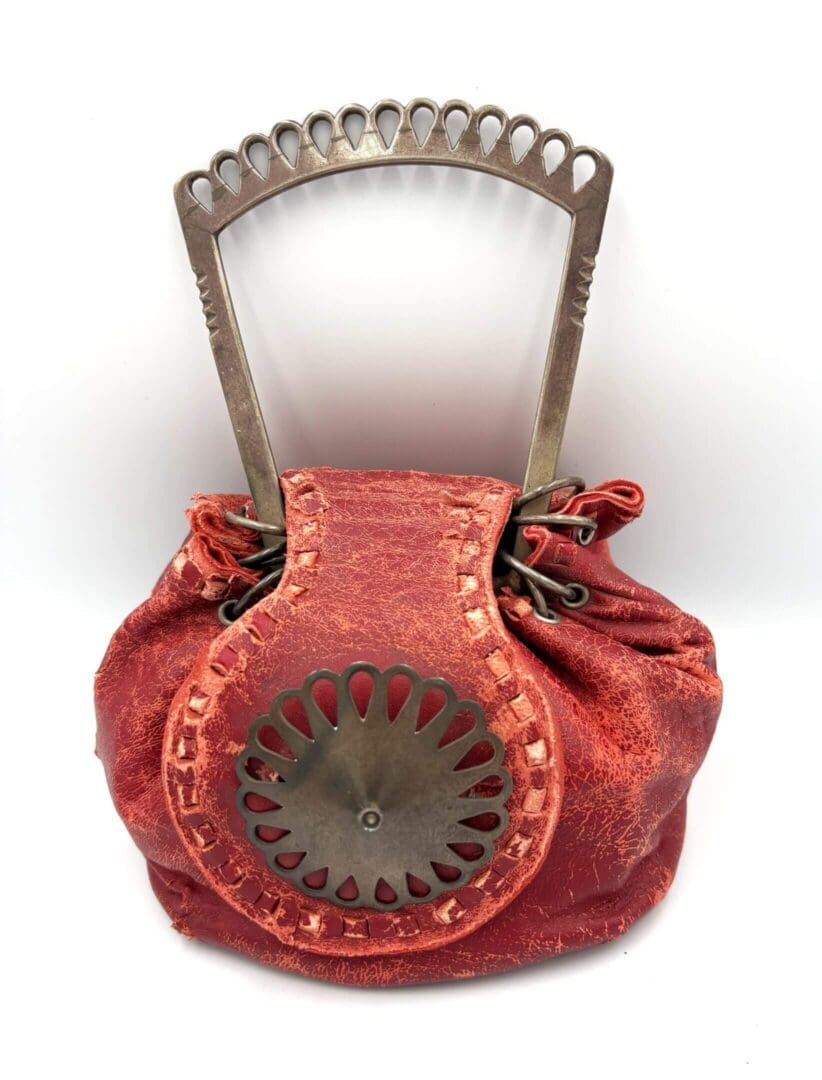 Red drawstring bag with decorative metal handle.