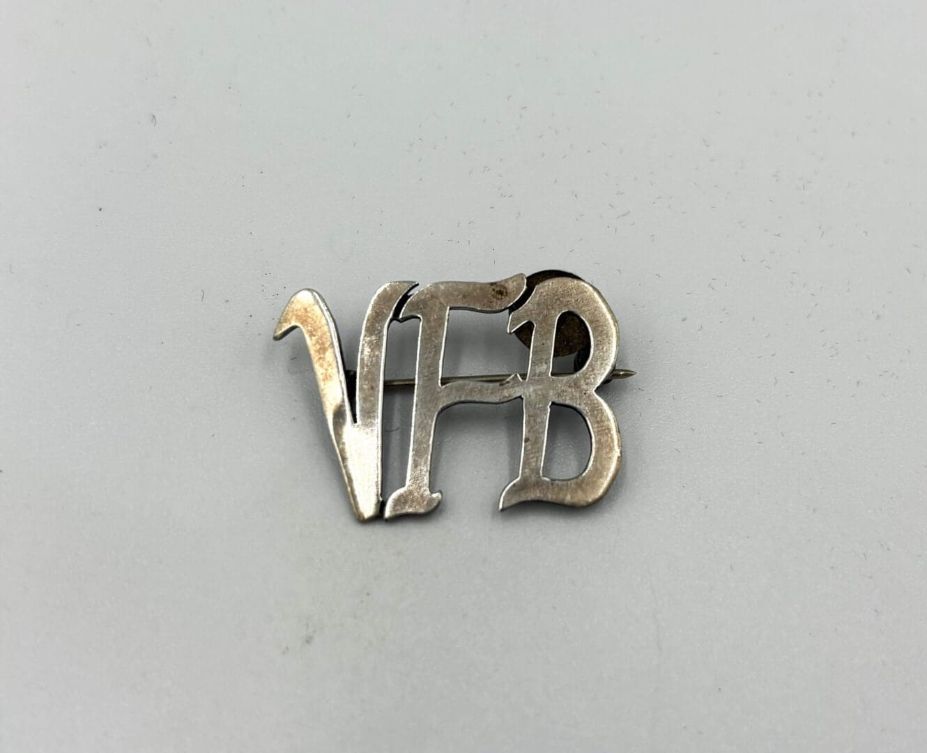Silver pin with "VFB" letters.