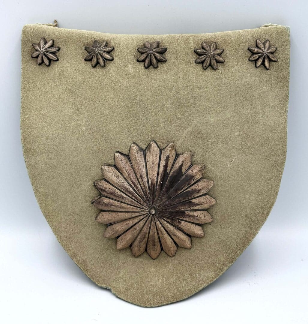 Decorative shield with embossed floral design.