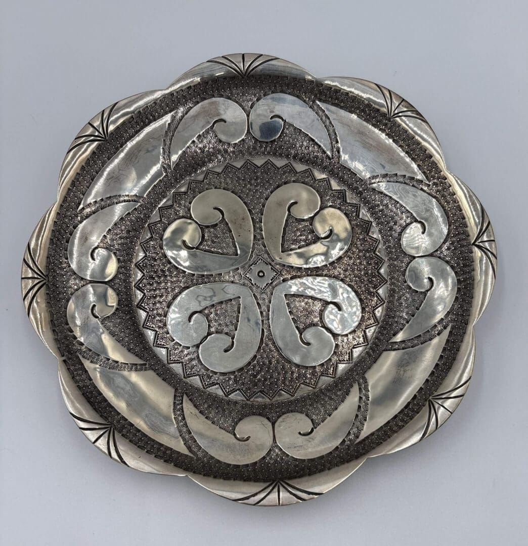 Ornate silver plate with intricate floral design.