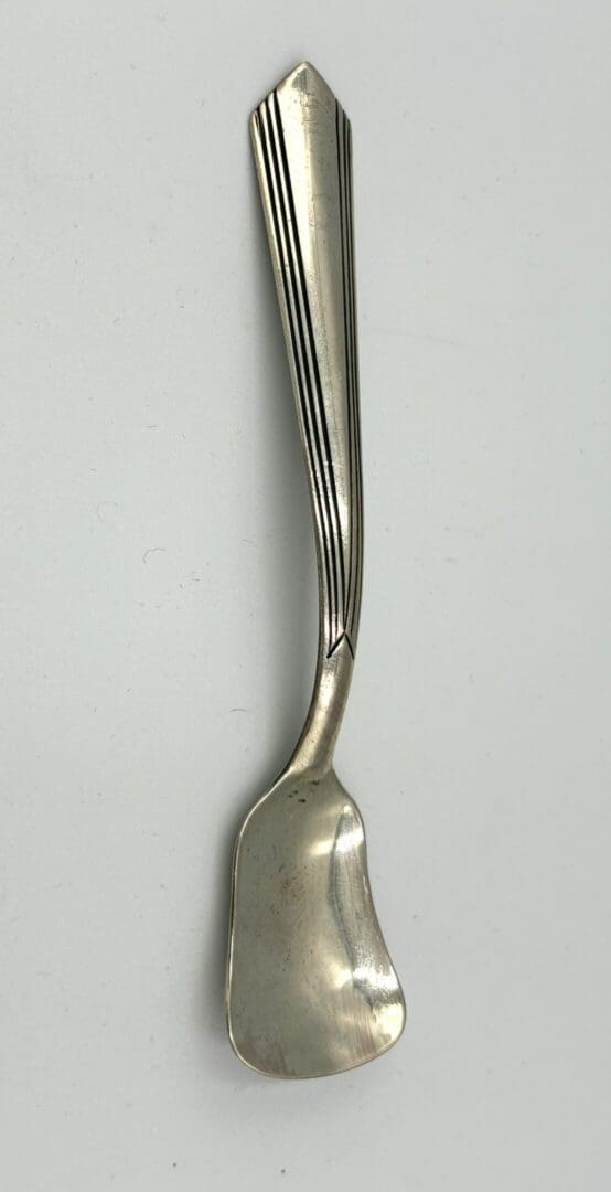 Silver butter spreader with decorative handle.