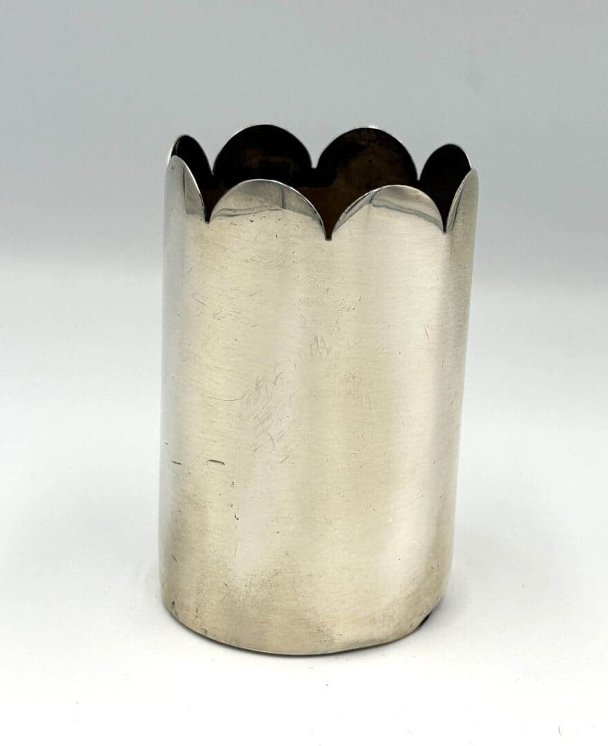 Scalloped-edge silver cylindrical container.