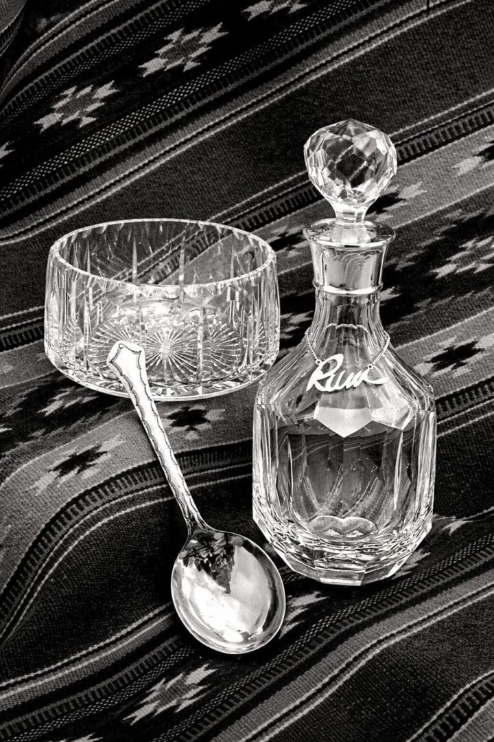 Crystal decanter, bowl, and spoon on fabric.