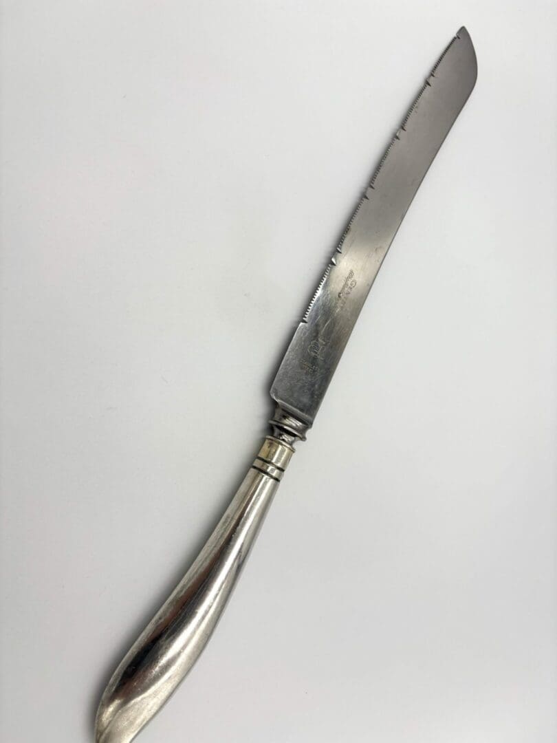 Silver butter knife with curved blade.