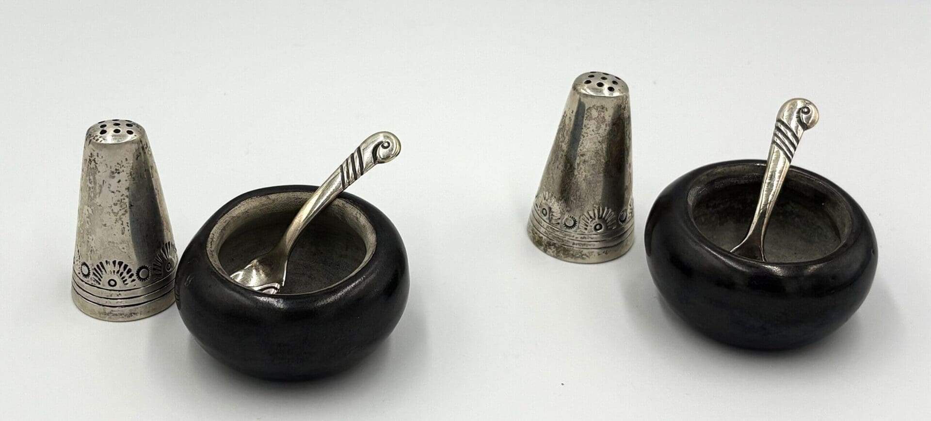 Silver salt shakers and bowls with spoons.