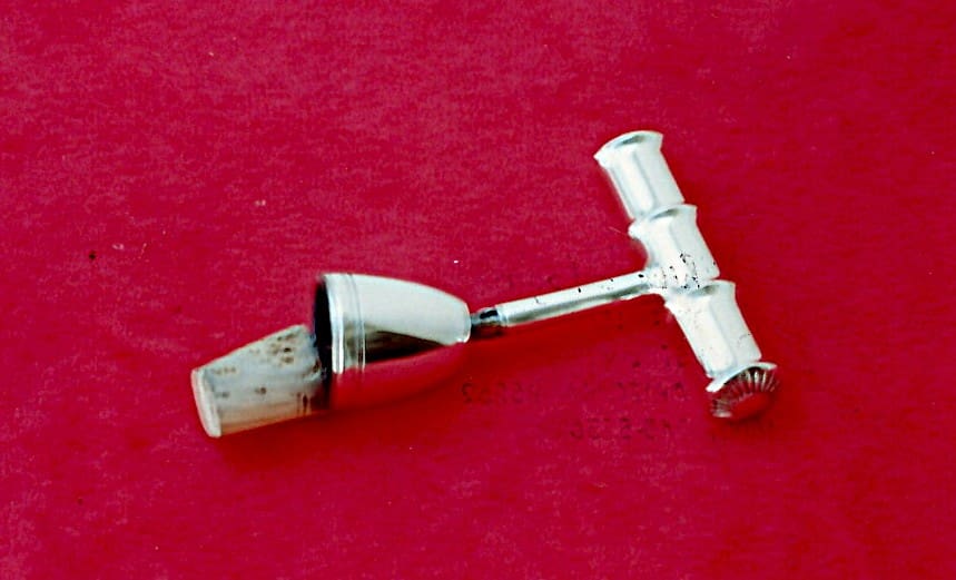 Silver and wood pipe on red background.