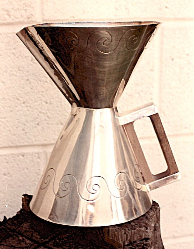 Silver decorative jug with engraved swirls.