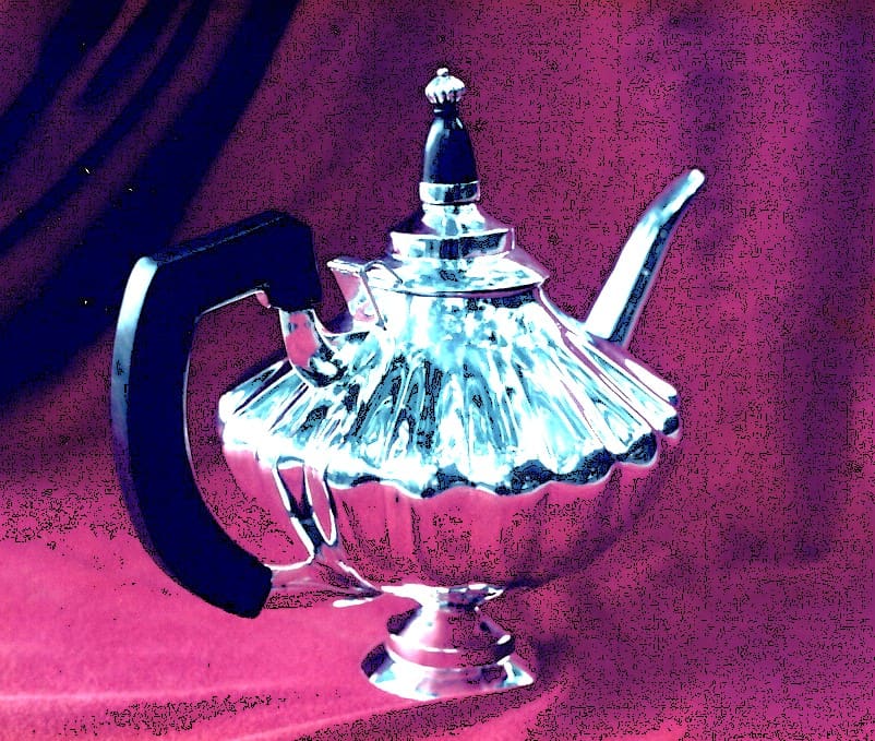 Silver teapot on a red background.