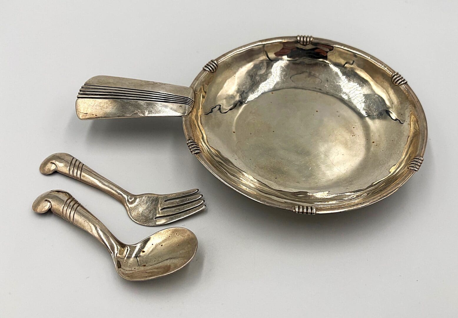 Silver baby dish with fork and spoon.