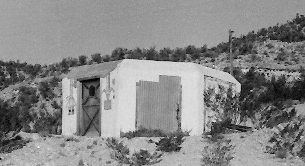 Small concrete building in a desert landscape.