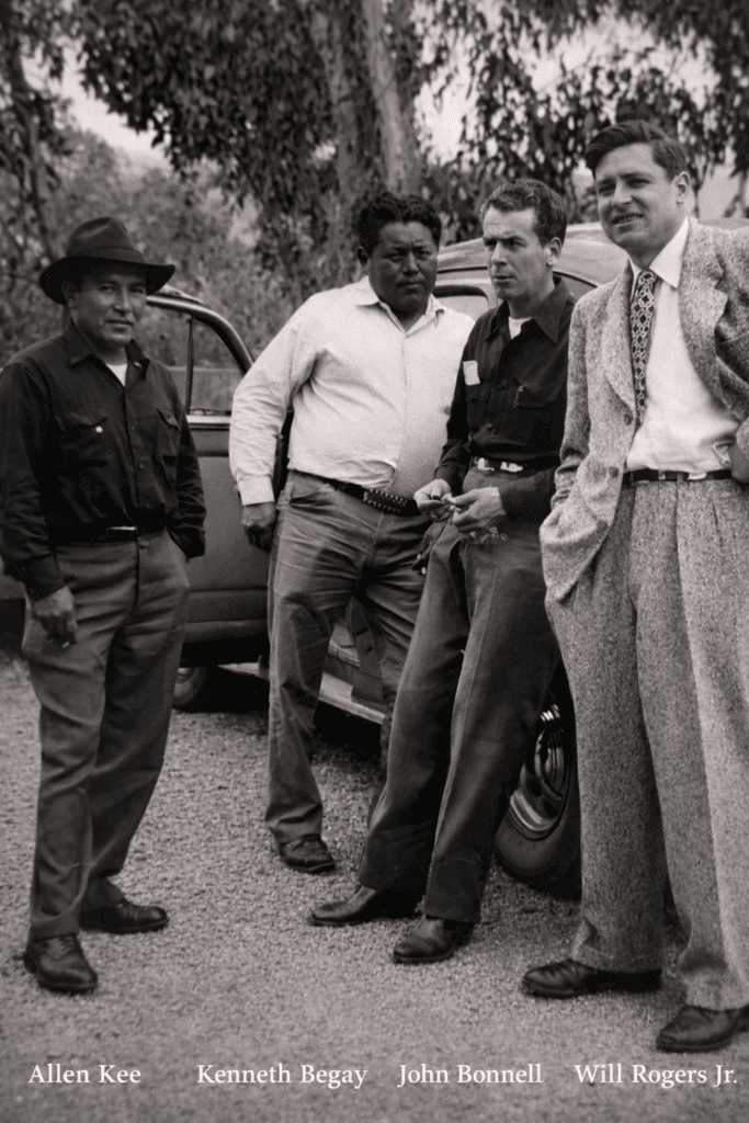 Four men standing beside a vintage car.