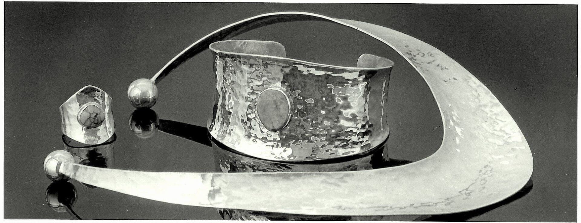 Hammered silver jewelry set on display.