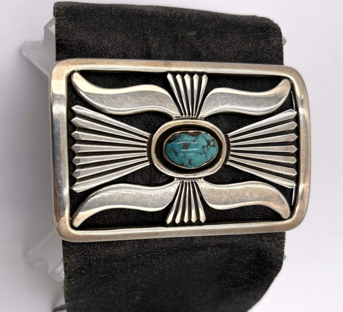 Silver belt buckle with turquoise stone design.