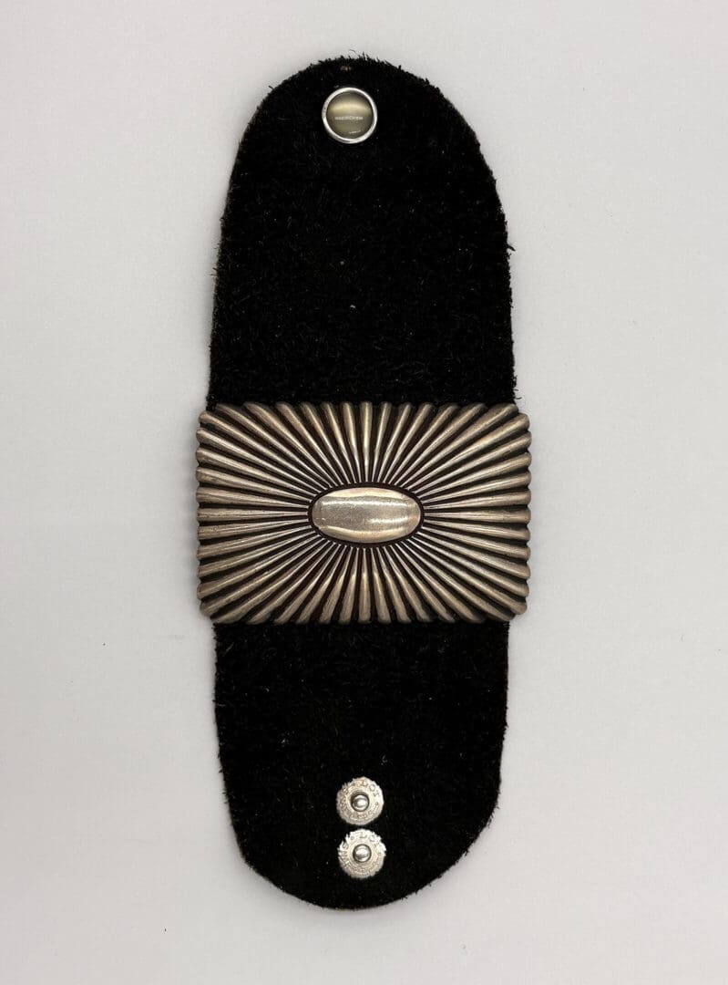Decorative black strap with metallic embellishment.