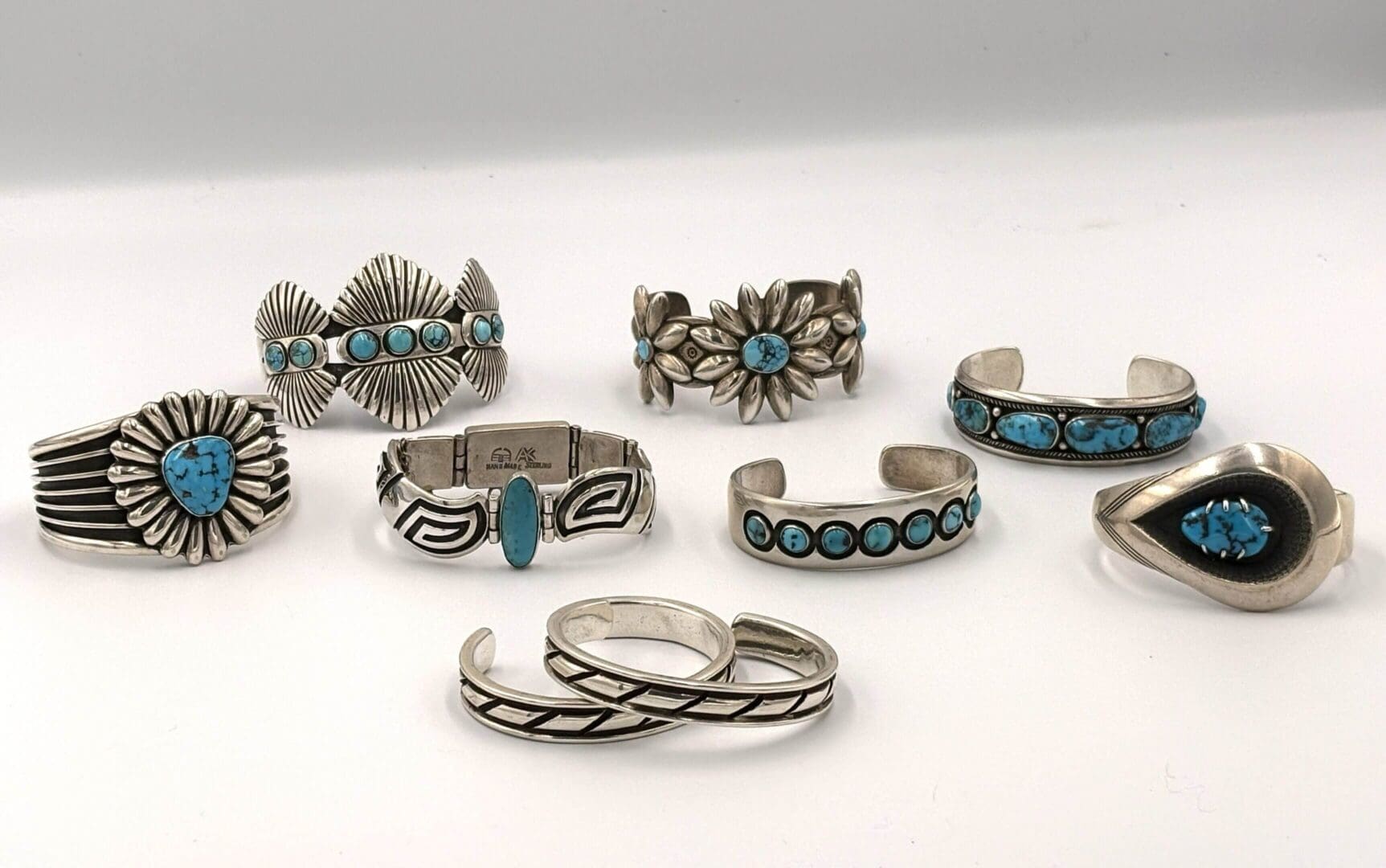 Silver rings with turquoise stone accents displayed.