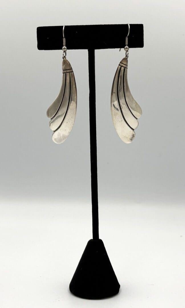 Silver earrings on black display stand.
