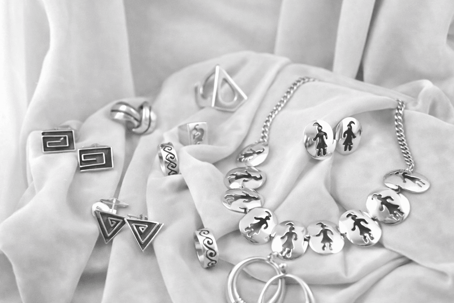 Silver jewelry set on soft fabric.
