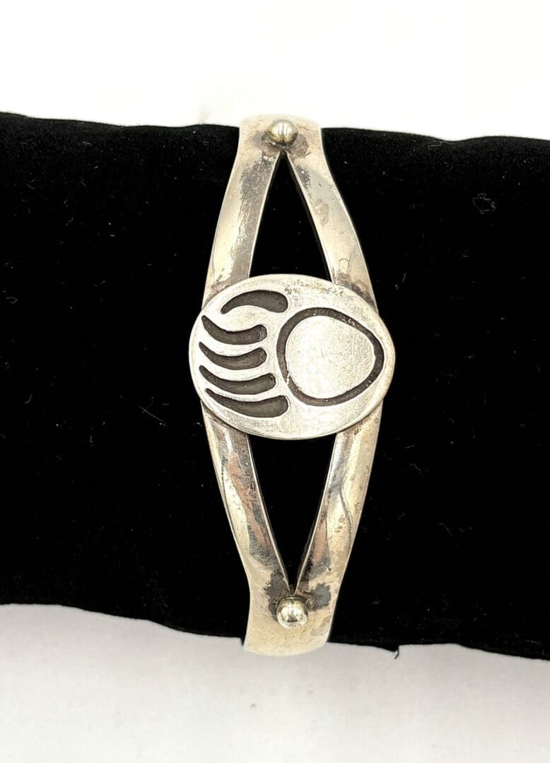Silver bracelet with abstract design on black.