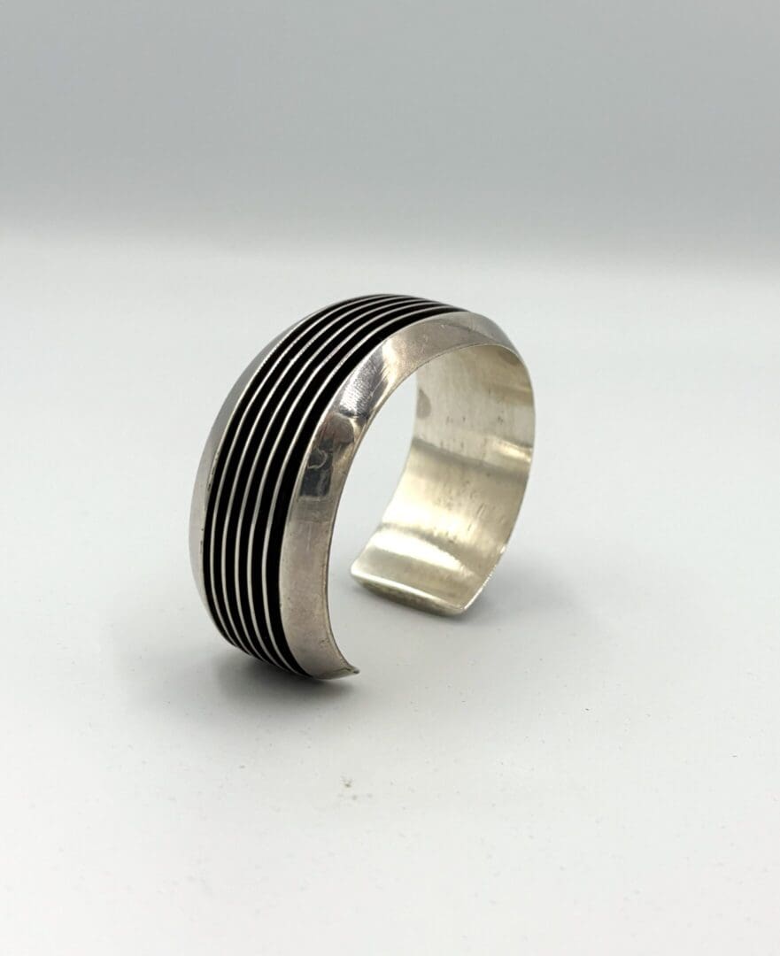 Silver cuff bracelet with black grooves.