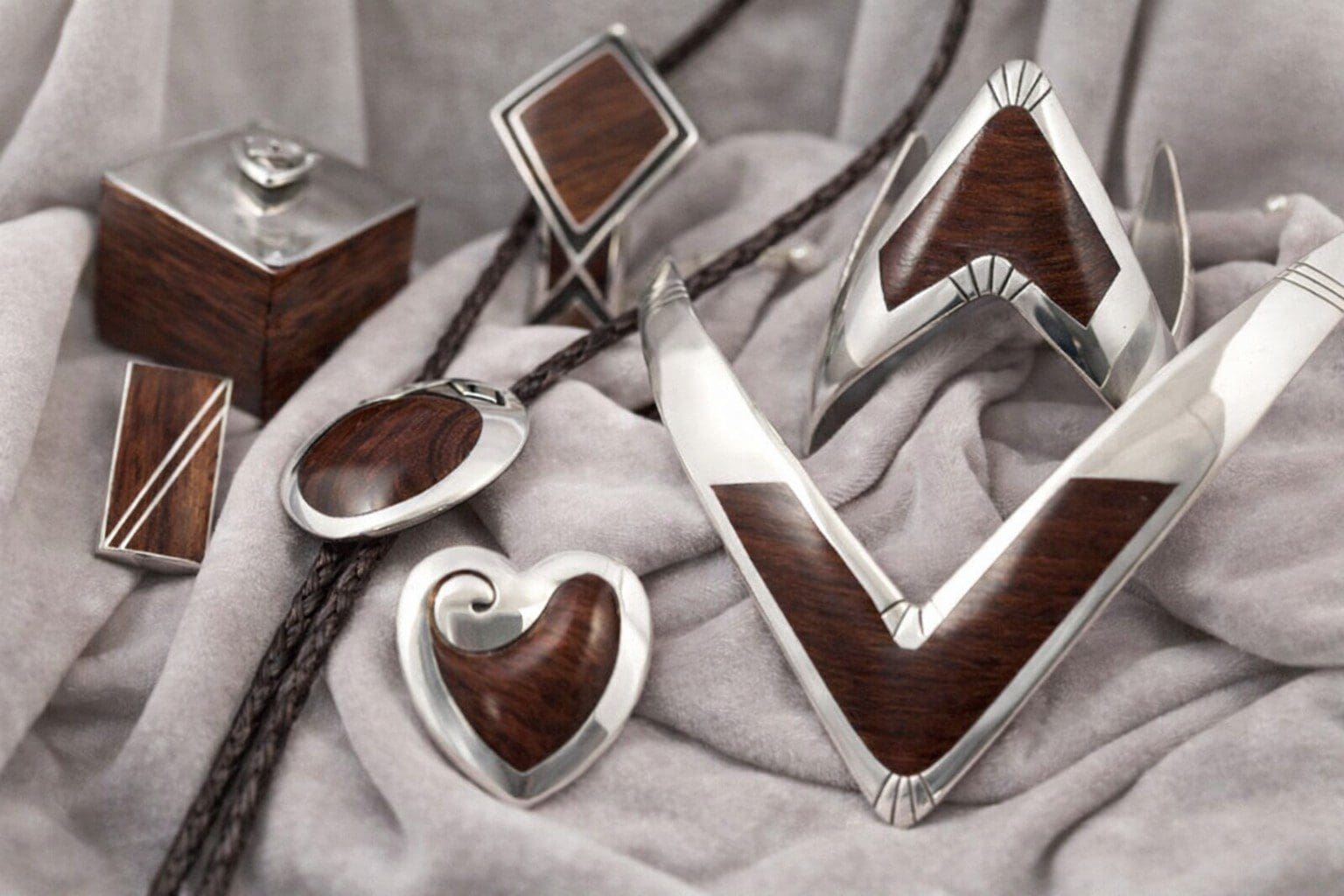 Silver and wood jewelry on fabric background.