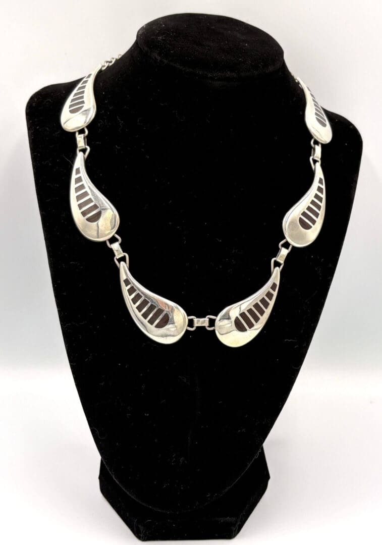 Silver necklace on black display stand.