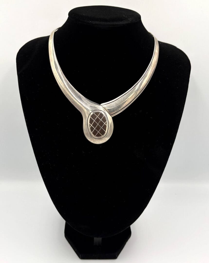 Silver necklace on a black display stand.