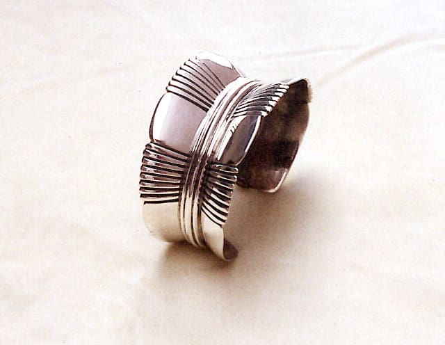 Silver cuff bracelet with intricate design.