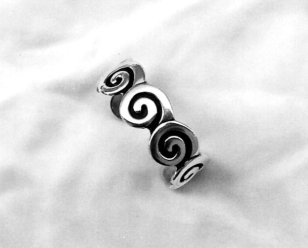 Silver spiral design ring on fabric background.