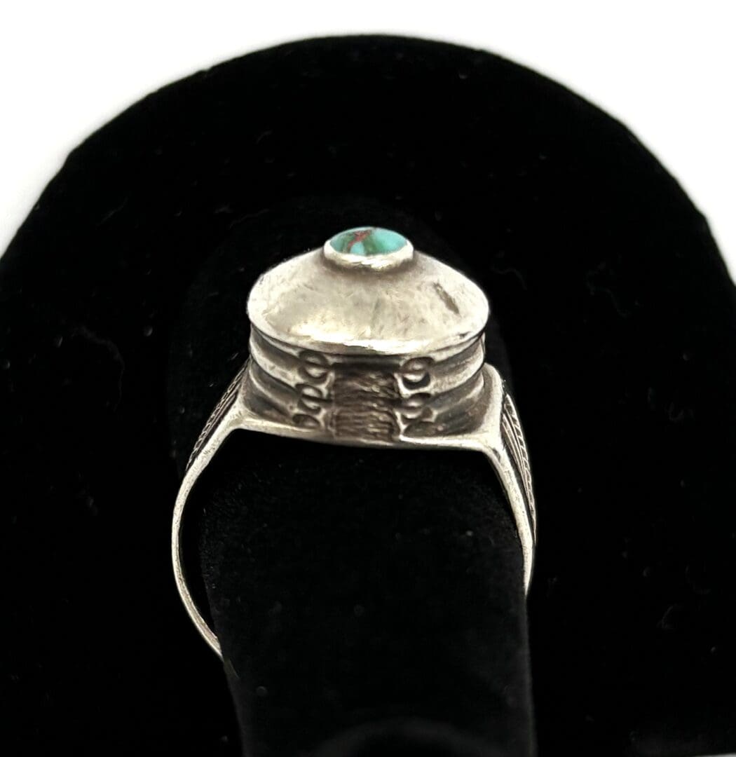 Silver ring with green gemstone on display.