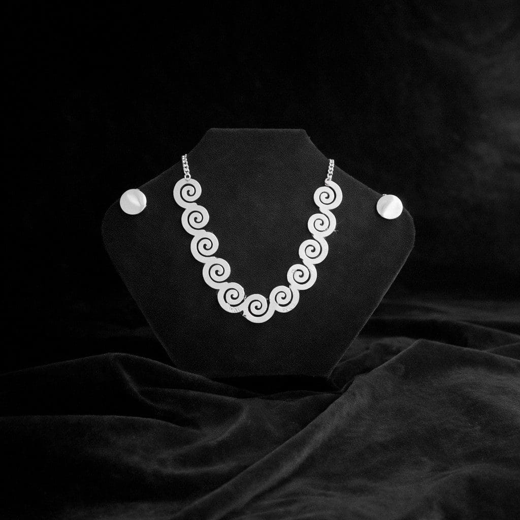 Silver spiral necklace on black velvet display.
