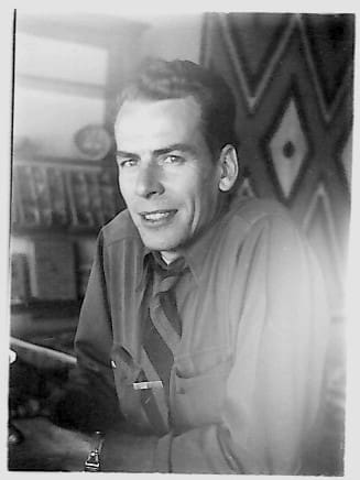 Smiling man posing in a patterned room.