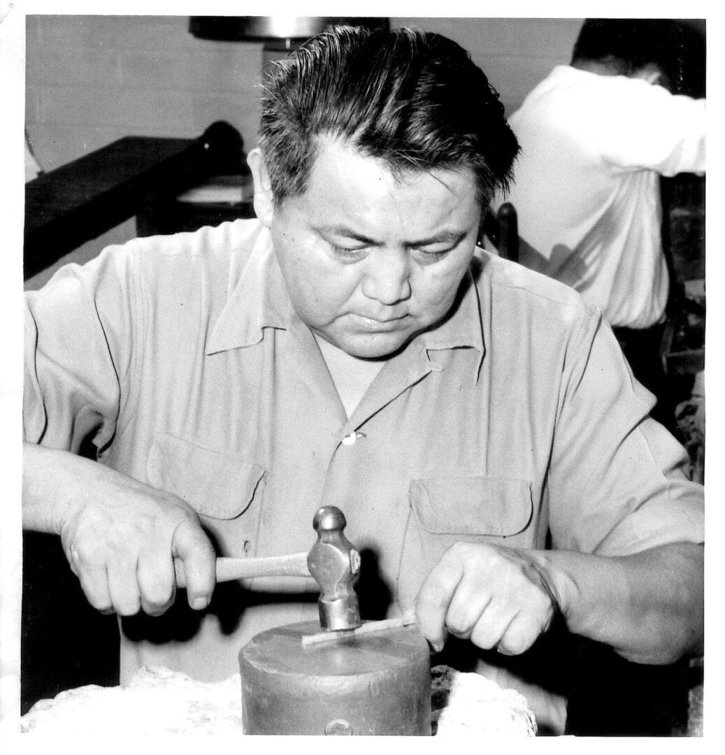 Man crafting with hammer and metal tool.