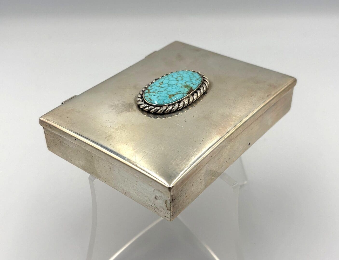 Silver box with turquoise stone embellishment.
