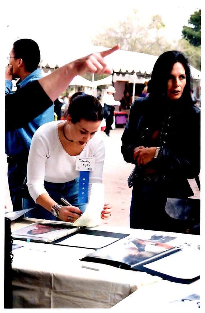 People at outdoor event table with photos.