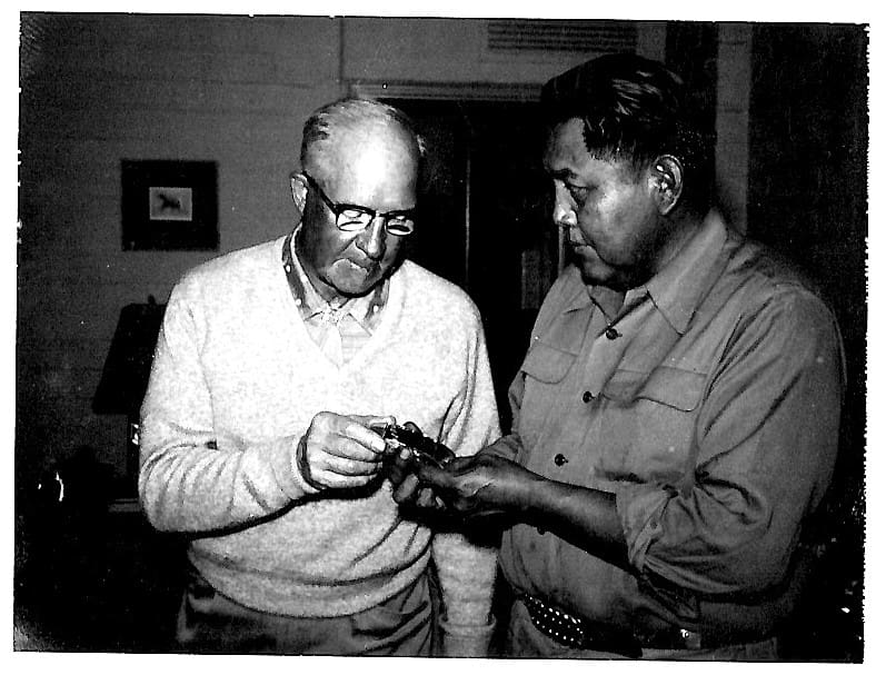 Two men examining an object together indoors.