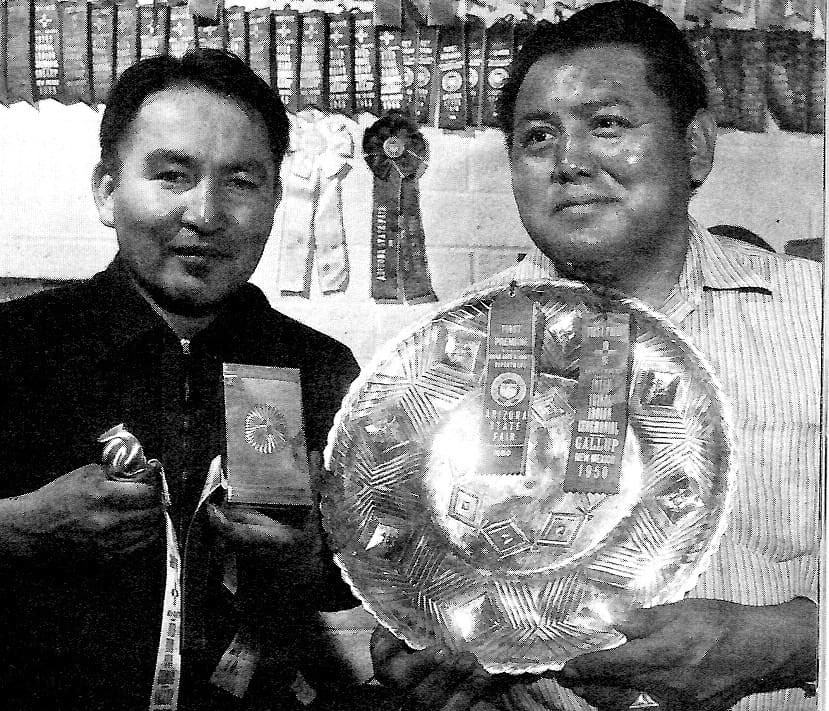 Two men holding awards and ribbons.