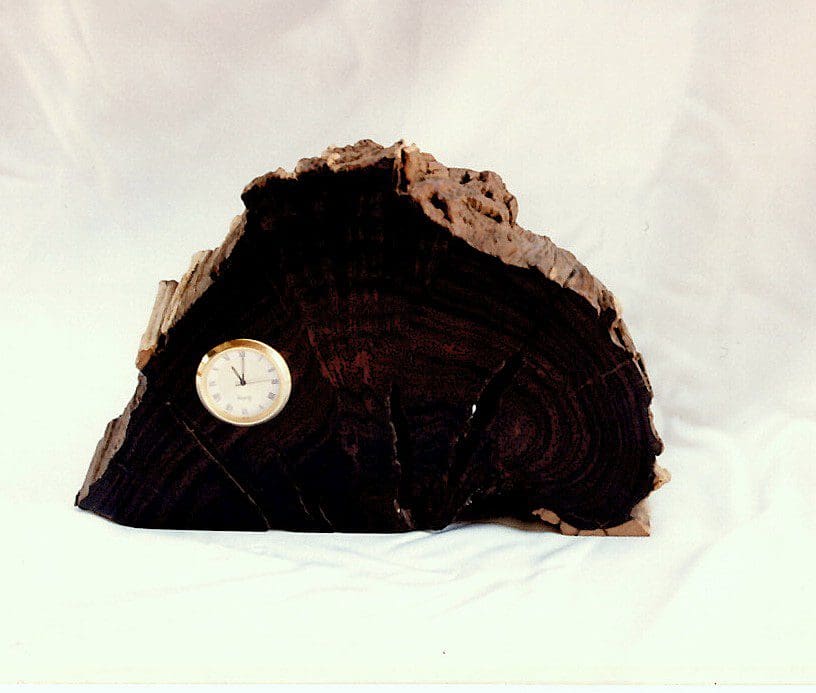 Rustic clock embedded in dark wood slab.