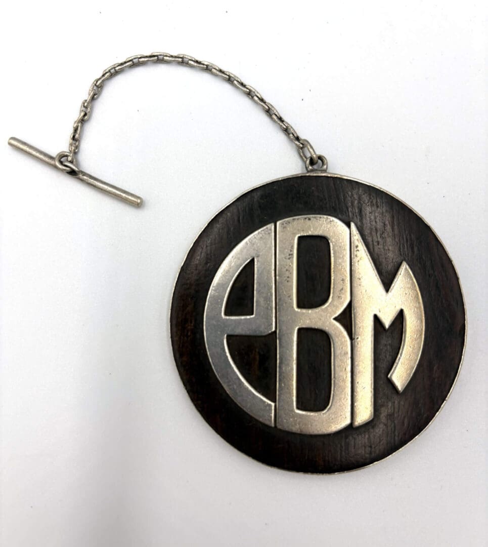 Circular pendant with chain, letters "EBM".