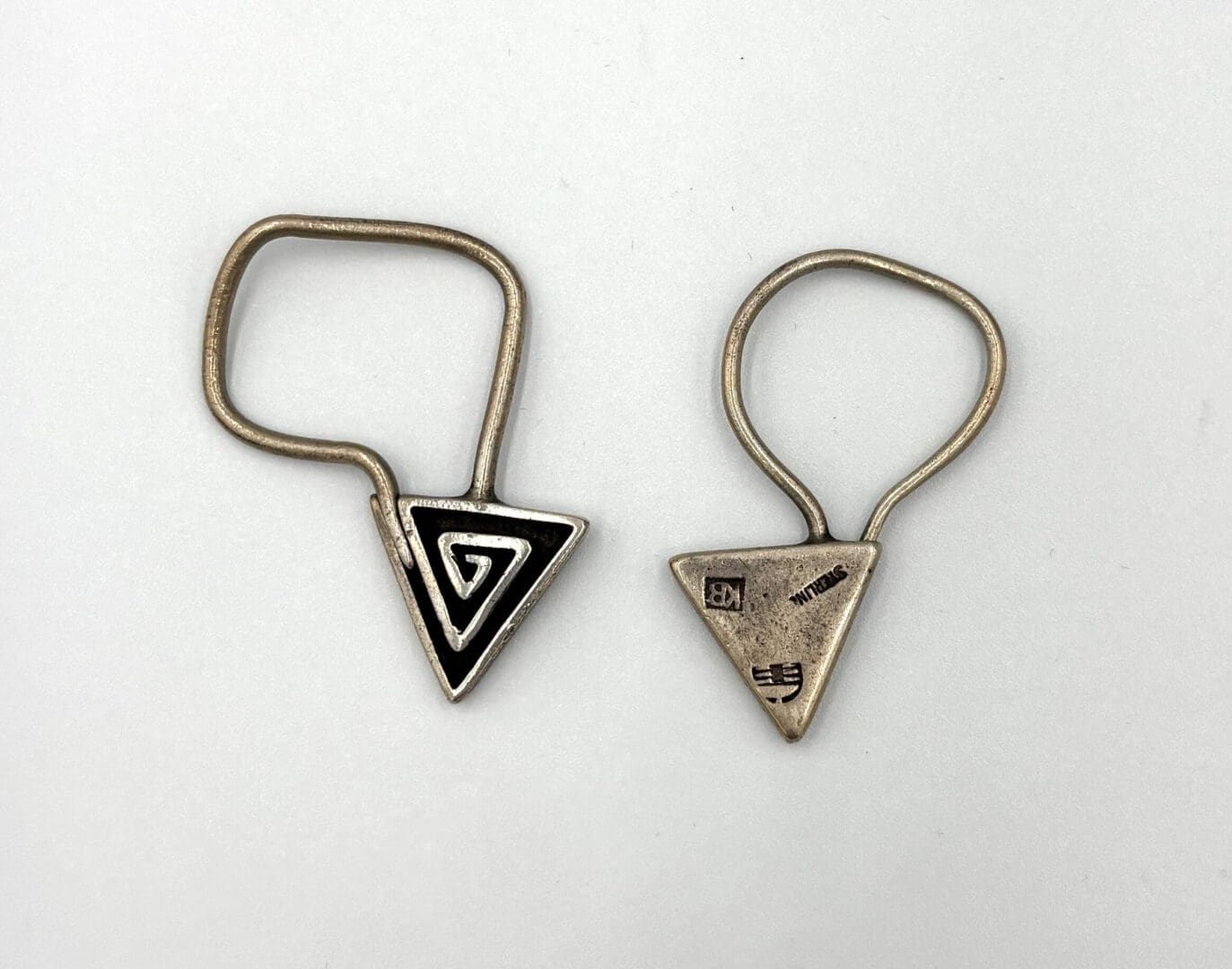 Two triangular metal keychain holders, engraved designs.