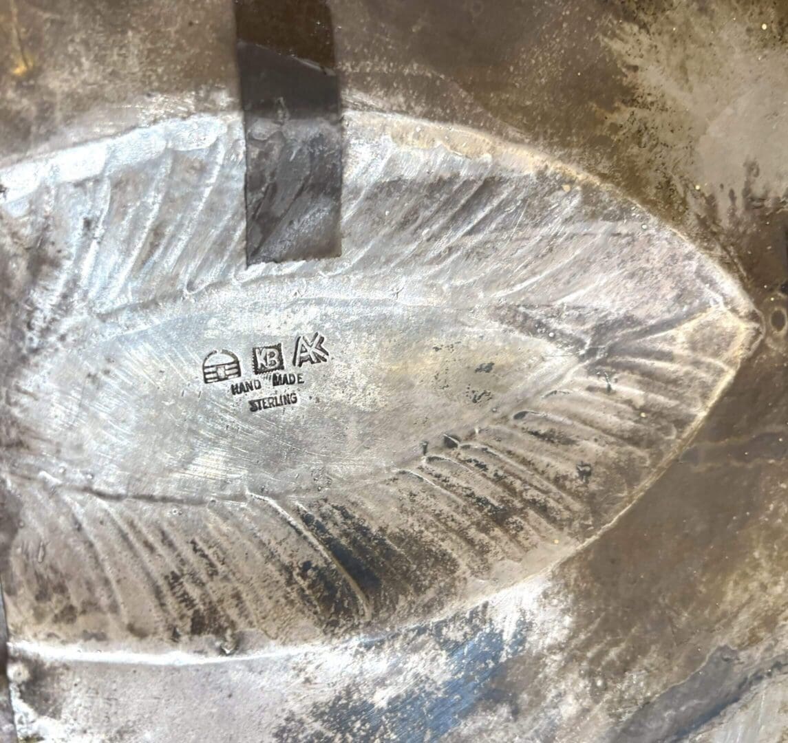 Silver engraving with "Hand Made Sterling" markings.