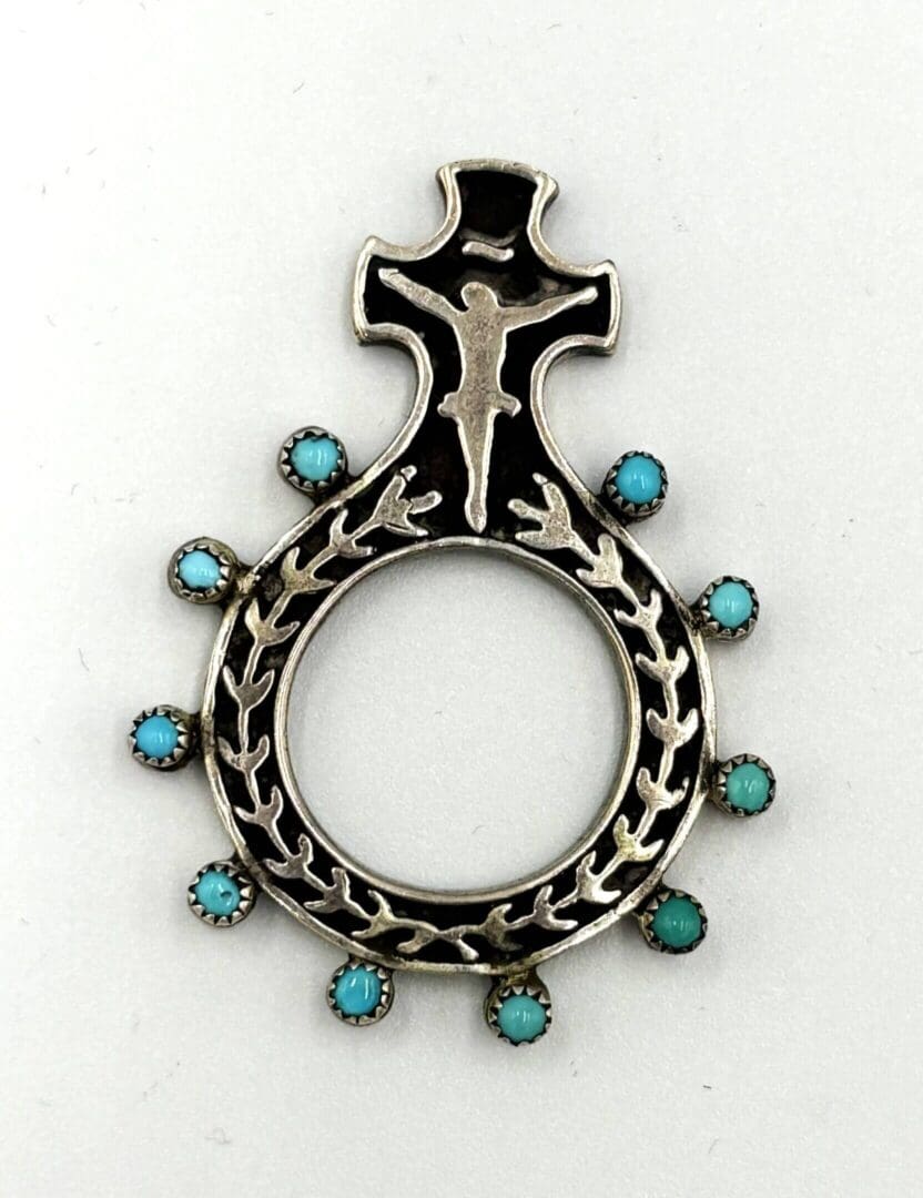 Silver pendant with turquoise stones and cross.
